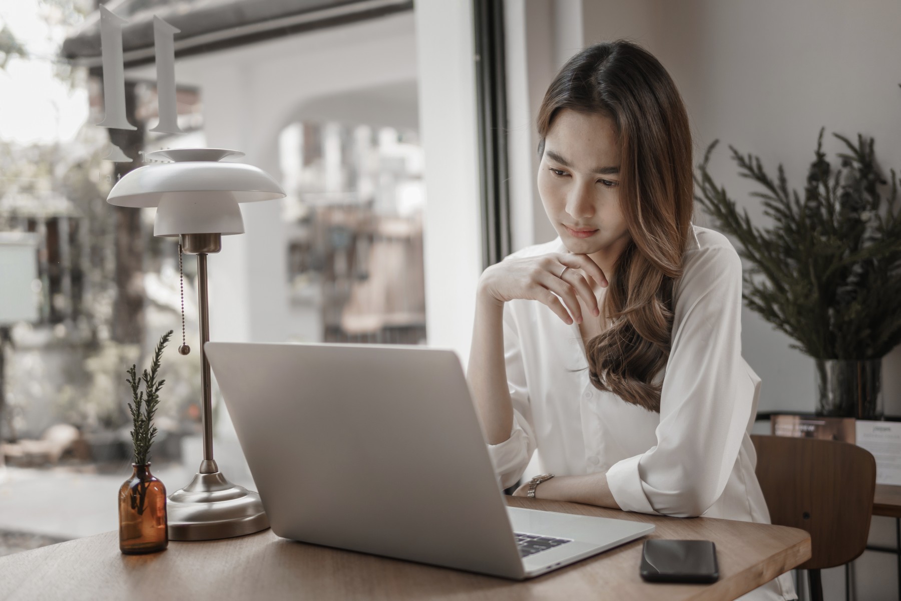 faqs　ノートパソコンで仕事をしながら考えている女性のイメージ